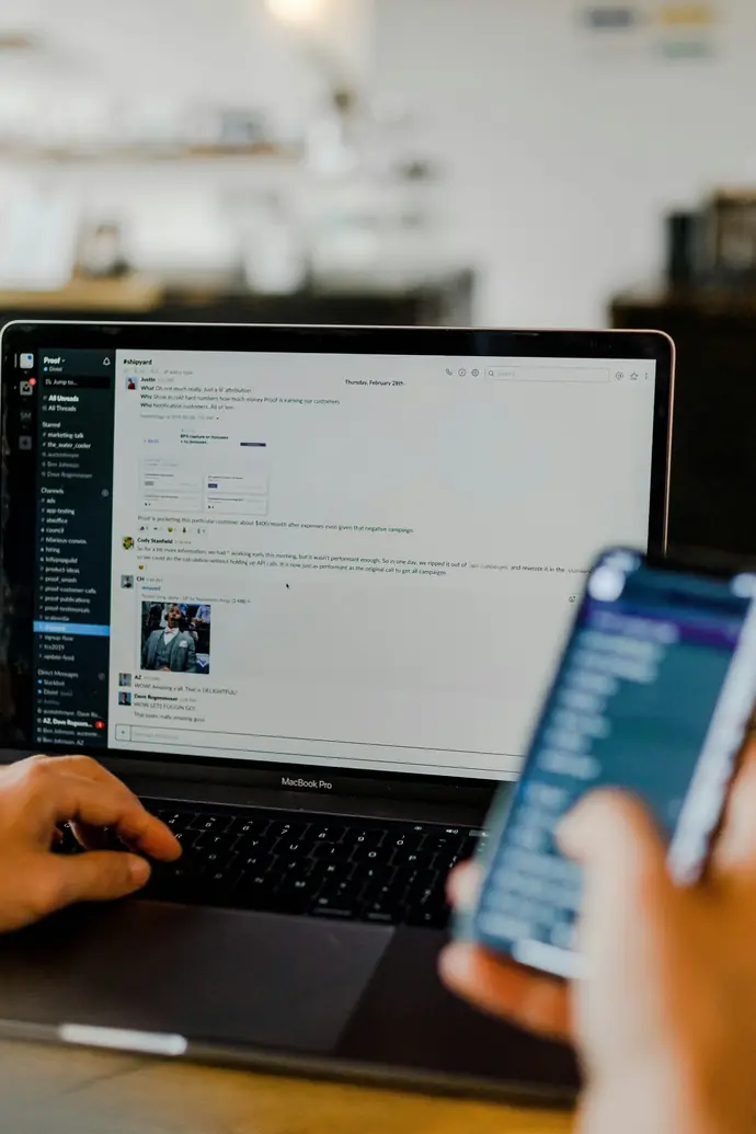Person arbeitet parallel an Laptop und Smartphone